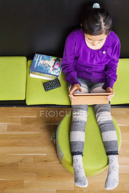 Asian girl sitting with tablet — Stock Photo