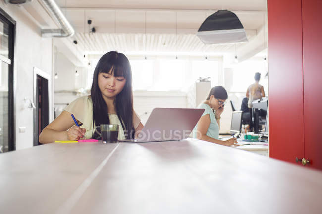 Woman writing notes on desk — Stock Photo