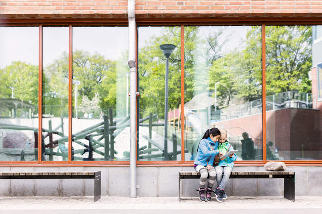 Meninas usando tablet digital no pátio da escola — Fotografia de Stock