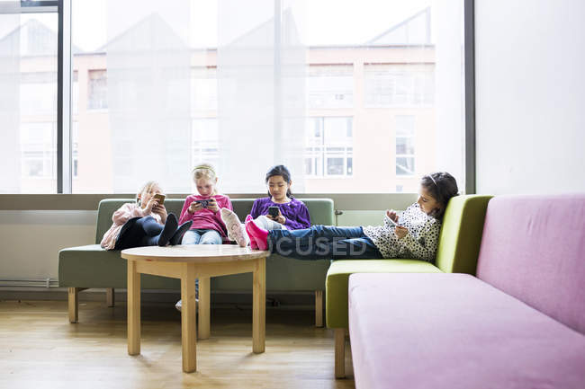 Mädchen sitzen mit Smartphones auf Sofa — Stockfoto