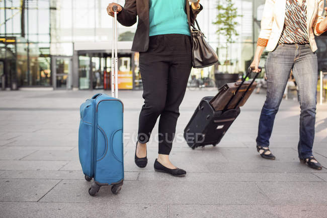 Businesswomen walking with suitcases — Stock Photo