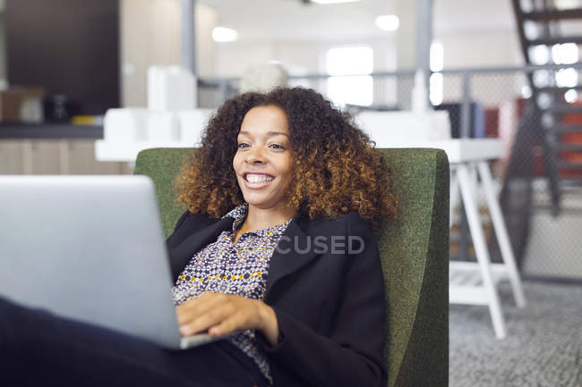 Woman smiling while using laptop — Stock Photo