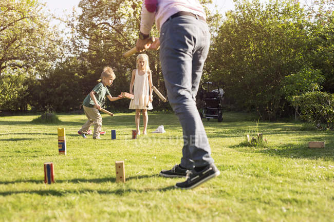 Bambini che giocano Kubb in giardino con il padre — Foto stock