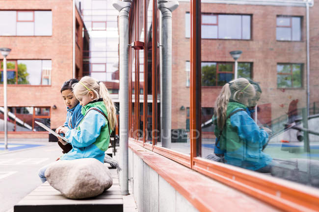 Girls using digital tablet in school yard — Stock Photo