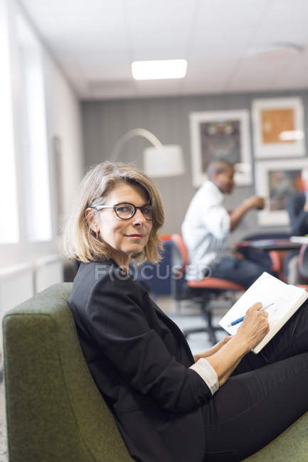 Зрелая женщина пишет в блокноте — стоковое фото