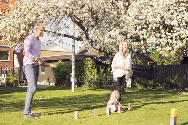 Girl playing Kubb on grass with parents — Stock Photo