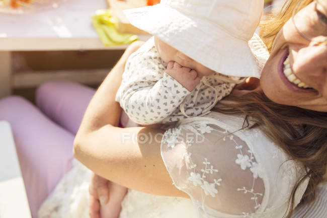 Женщина держит малышку на вечеринке в саду — стоковое фото