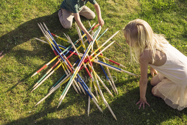 Boy and girl playing giant pick up sticks — Stock Photo