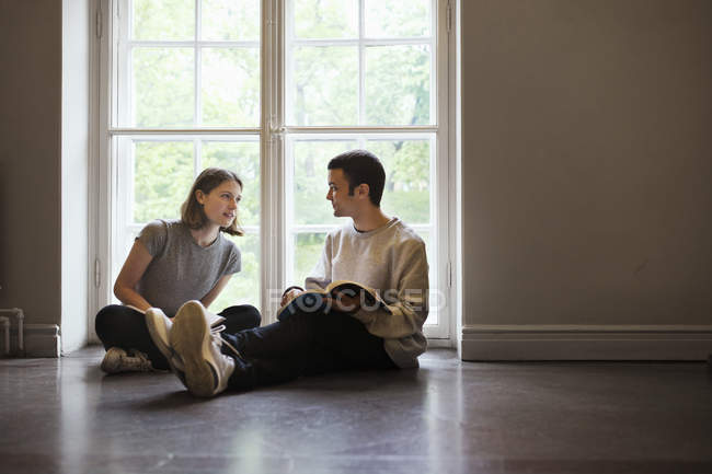 Zwei Studenten sitzen auf dem Boden und unterhalten sich in der Universität — Stockfoto