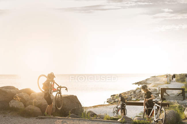 Cyclists walking on coastline — Stock Photo