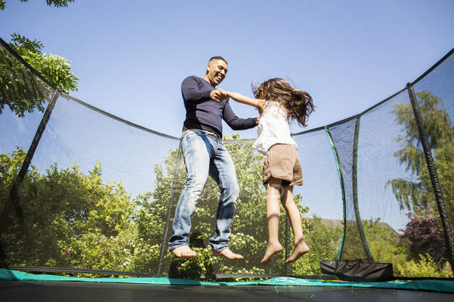 Батько з дівчиною стрибає на батуті — стокове фото