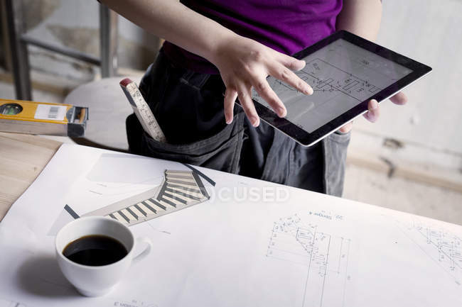 Frau schaut sich Bauplan auf Tablet an — Stockfoto