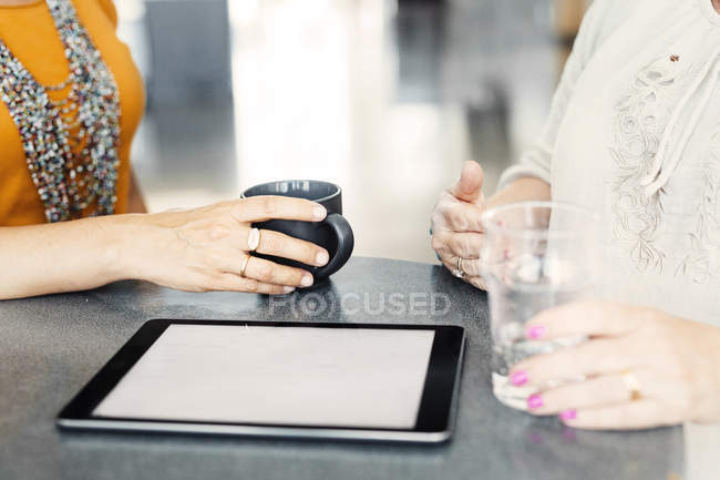 Коллеги сидят за столом с планшетом — стоковое фото