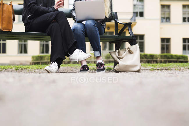 Dois estudantes sentados no pátio da escola com laptop e xícara de café — Fotografia de Stock