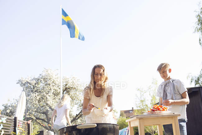 Mujer madura y adolescente preparando comida en la fiesta del jardín - foto de stock