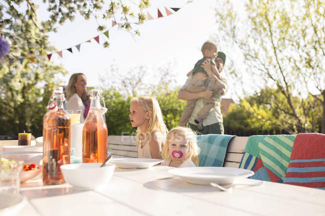 Children sitting at dinner table at garden party in back yard — Stock Photo