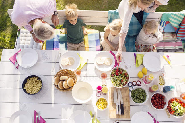 Vista superior de la familia sentada en la mesa de la cena en la fiesta del jardín en el patio trasero - foto de stock