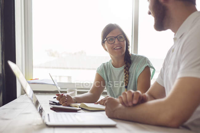 Coworkers sitting at table with laptops — Stock Photo
