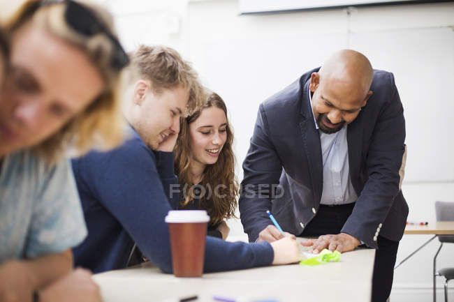 Students studying at desk with teacher — Stock Photo