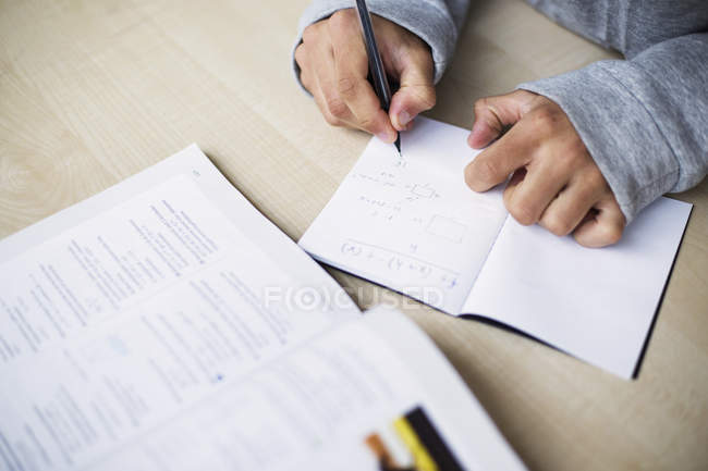 Close-up view of student writing in notebook at desk in classroom — Stock Photo