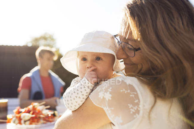 Woman holding baby girl at garden party — Stock Photo