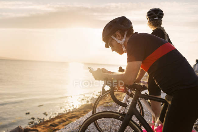 Radfahrer schreibt SMS am Meer — Stockfoto