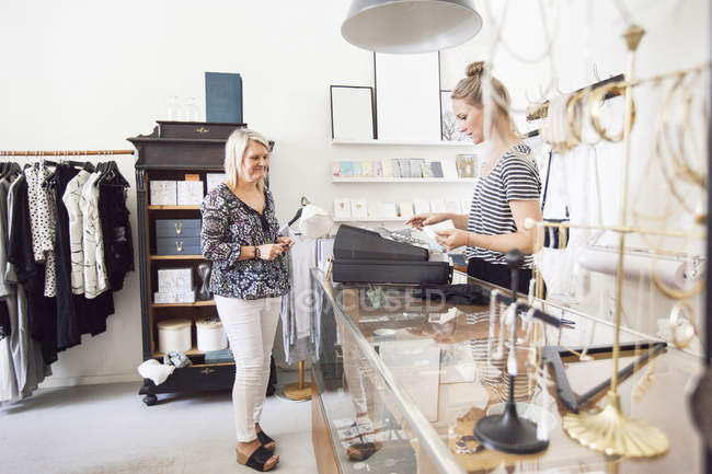 Woman standing by cash register — Stock Photo