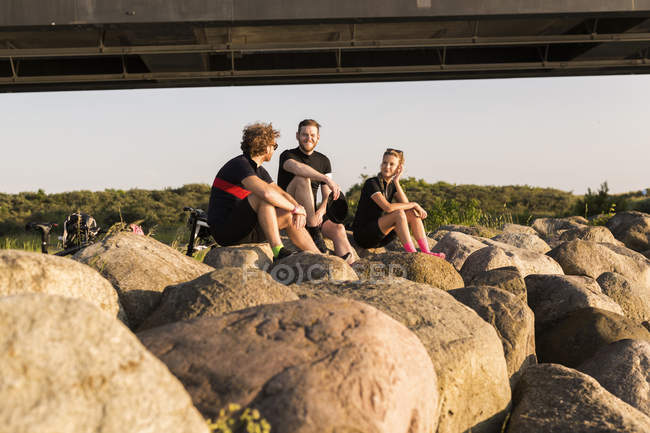 Велогонщики сидят на берегу на закате — стоковое фото