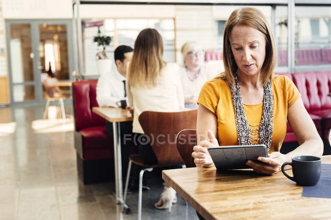 Frau benutzt Tablette in Cafeteria — Stockfoto