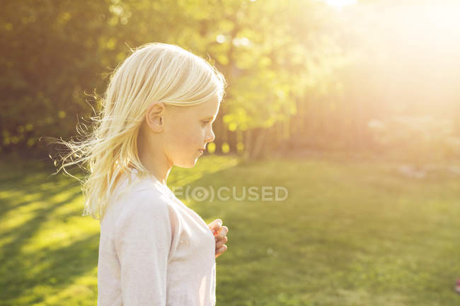 Vista lateral da menina loira no jardim — Fotografia de Stock