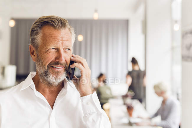 Hombre mayor hablando por teléfono en la cafetería - foto de stock