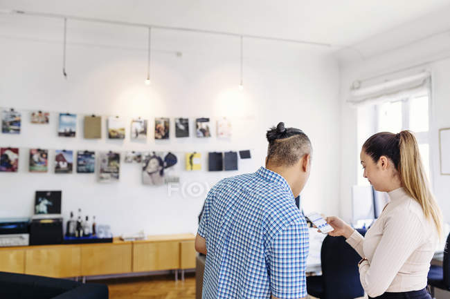 Coworkers looking at mobile phone in office — Stock Photo