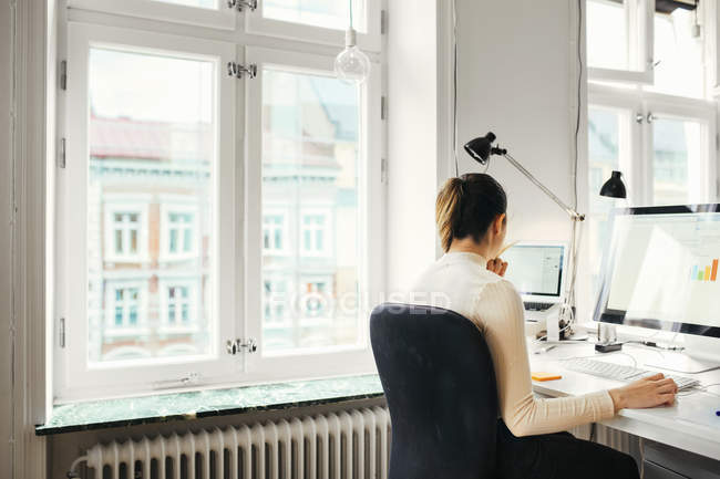 Жіночий редактор за допомогою комп'ютера в офісі — стокове фото