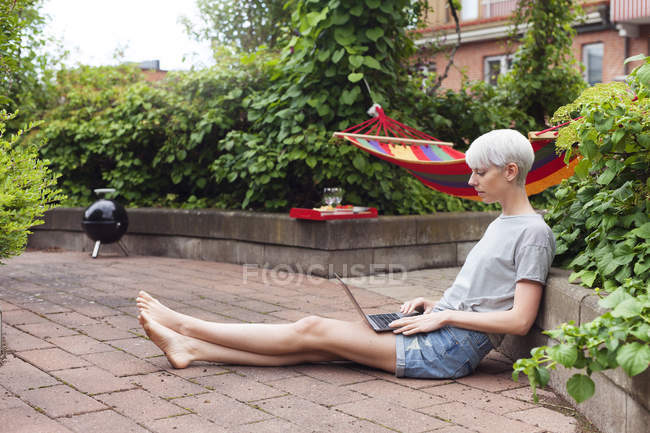 Woman sitting in garden and using laptop — Stock Photo