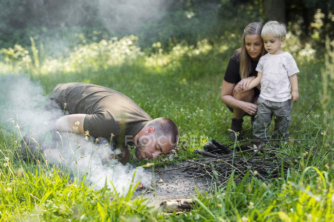 Homem acendendo fogo acampamento na floresta durante o dia — Fotografia de Stock