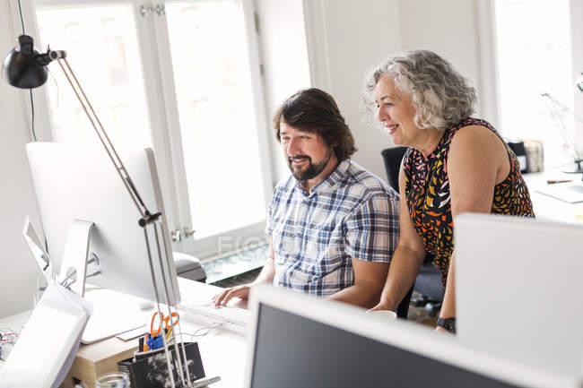 Colleagues using computer together in office — Stock Photo