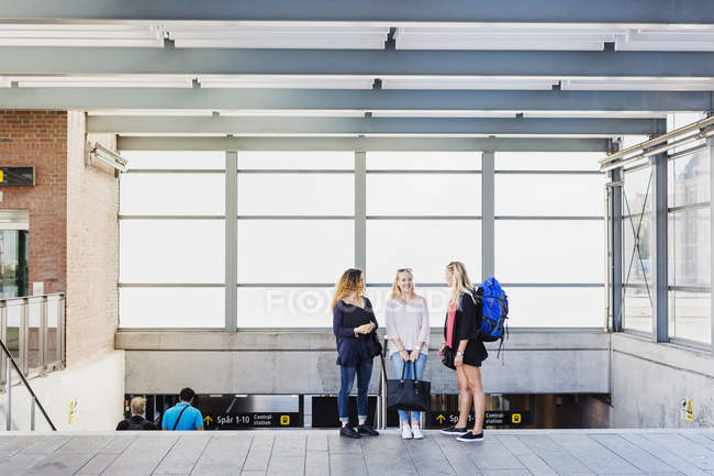 Three young women standing by stairs at station — Stock Photo