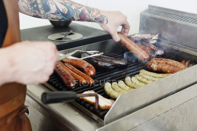 Partie médiane de l'homme préparant des saucisses sur le gril — Photo de stock