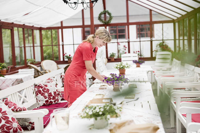 Frau deckt Tisch im Wintergarten — Stockfoto