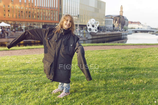 Menina sorridente (4-5) vestindo casaco de grandes dimensões — Fotografia de Stock