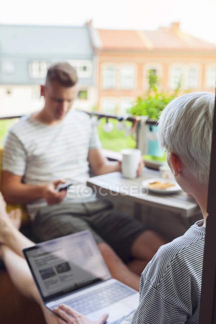 Couple using mobile devices on balcony — Stock Photo
