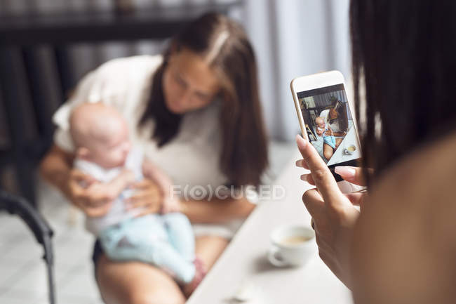 Femme photographe mère avec bébé fils (2-5 mois) dans le café — Photo de stock
