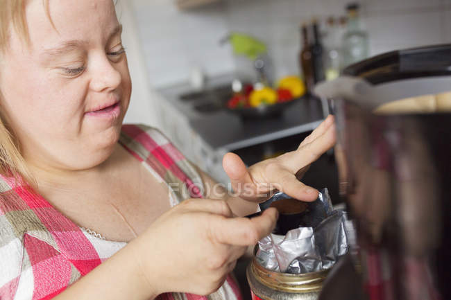 Взрослая женщина с синдромом Дауна готовит кофе на кухне — стоковое фото