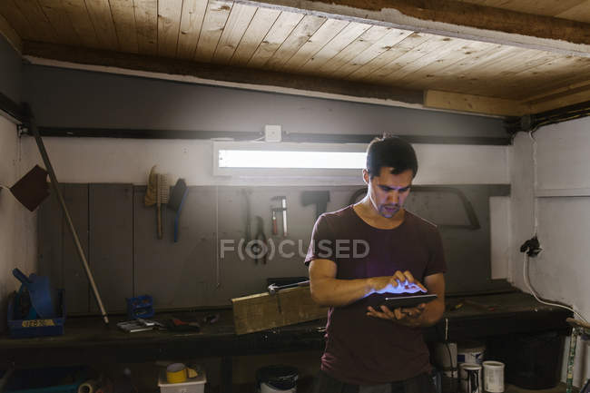Человек с помощью цифрового планшета в гараже — стоковое фото