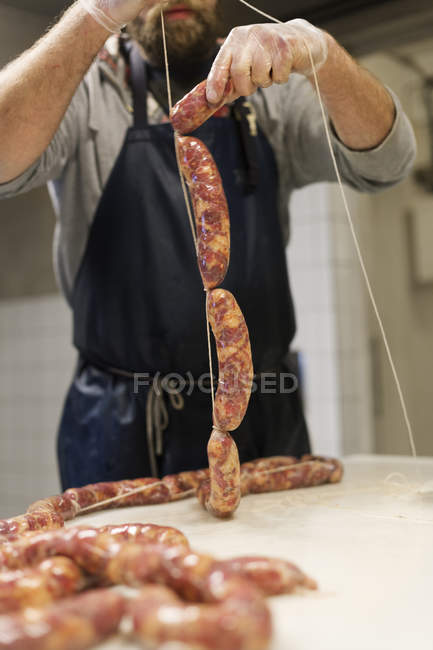 Sección media del hombre haciendo salchichas de cerdo - foto de stock