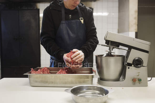 Середина людини, що формує м'ясо для приготування свинячих ковбас — стокове фото