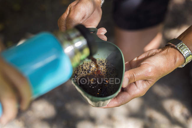 Junge Frau gießt Getränk aus isoliertem Getränkebehälter — Stockfoto