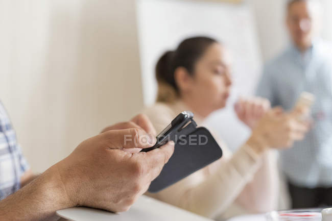 Hombre usando el teléfono móvil durante la reunión de negocios - foto de stock