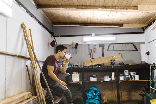 Чоловік п'є каву в гаражі — стокове фото