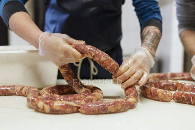 Mid section of men making pork sausages — Stock Photo